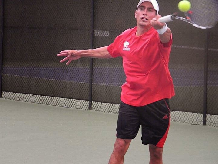 Aaron Krisan making forehand contact during an indoor tennis match