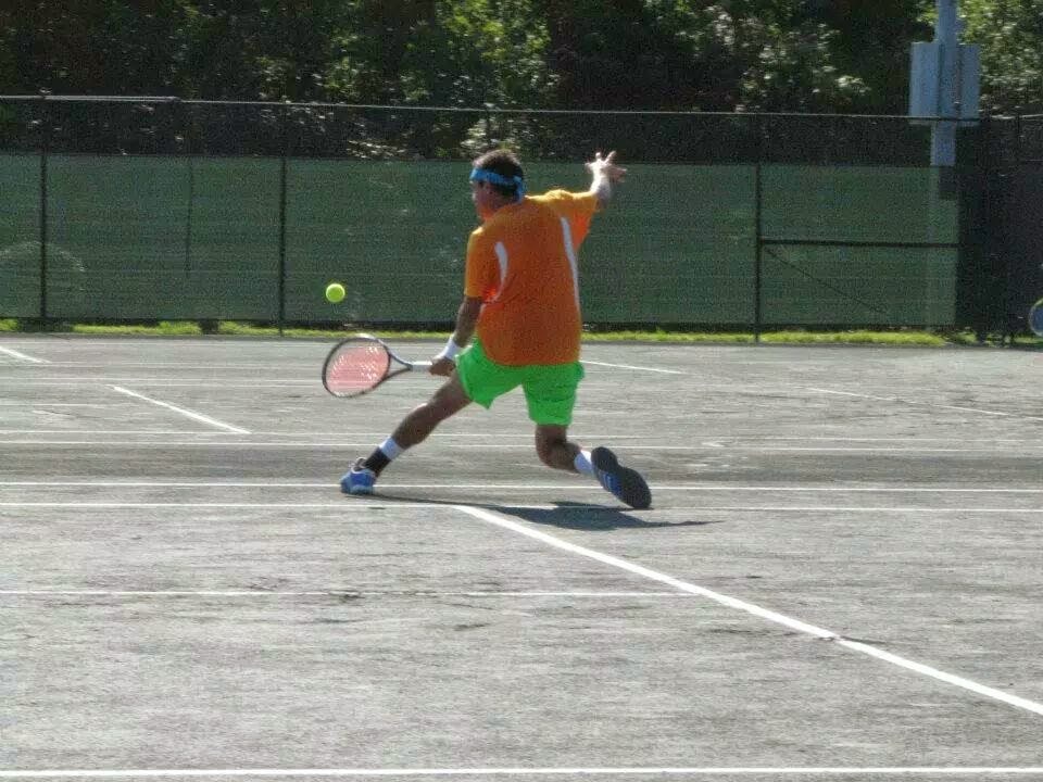 Aaron Krisan moving into a low forehand during an outdoor tennis match